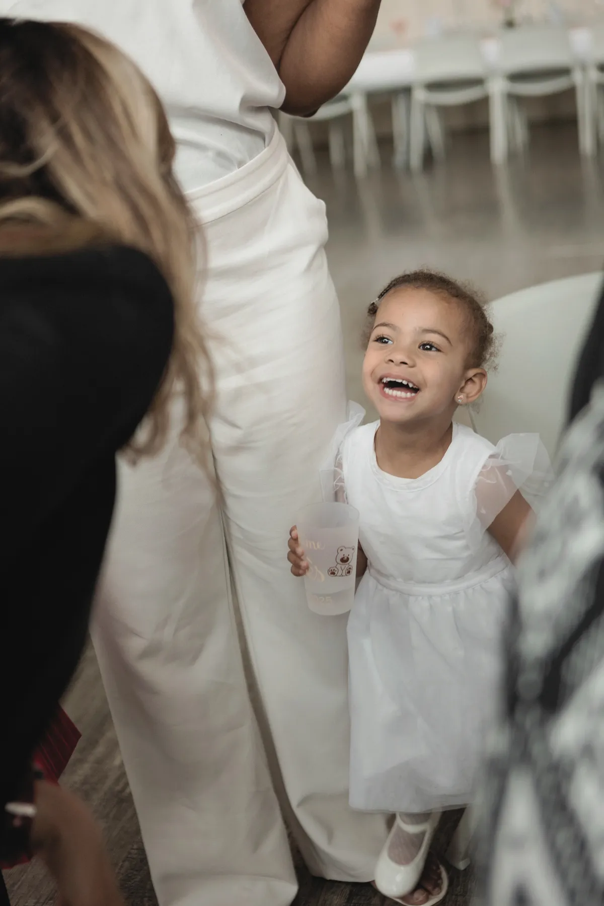 Petite fille en robe blanche qui rit le jour de son baptême